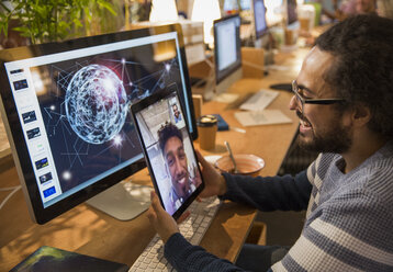 Grafikdesigner im Videochat mit einem Kollegen auf einem digitalen Tablet im Büro - CAIF21066