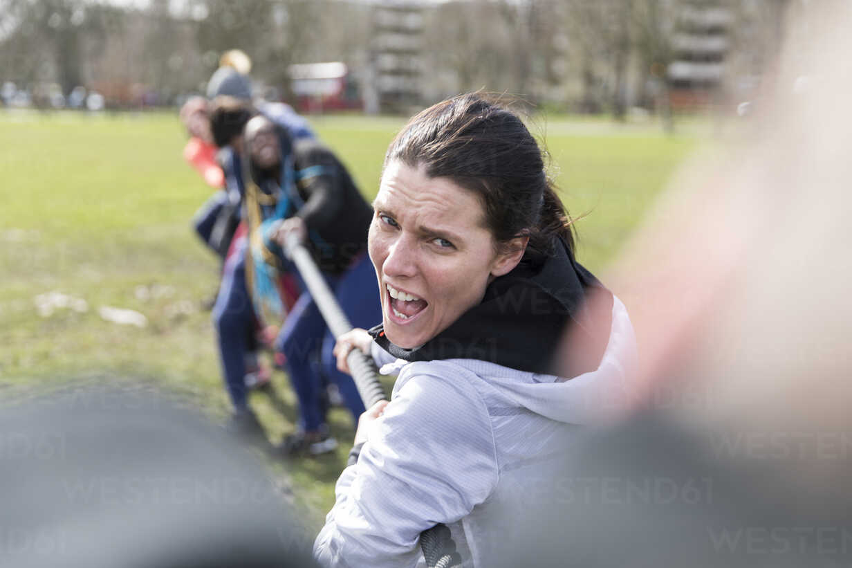 Determined woman enjoying tug-of-war in park stock photo