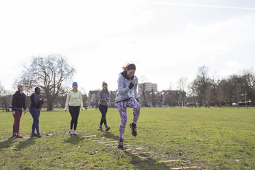 Focused woman doing speed ladder drill in sunny park - CAIF21123