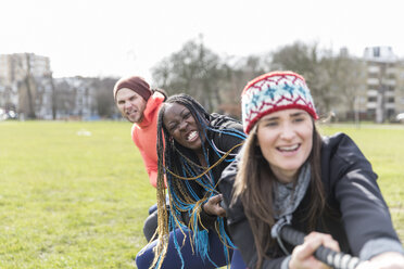 Determined team pulling rope in tug-of-war in park stock photo
