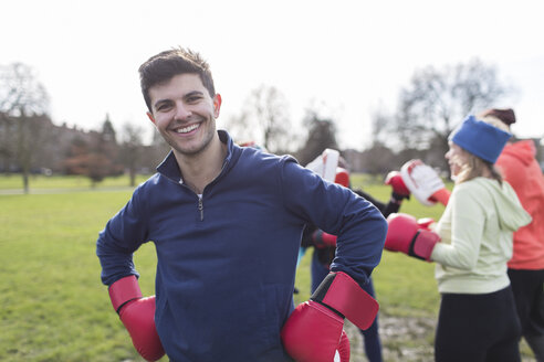 Porträt lächelnder, selbstbewusster Mann beim Boxen im Park - CAIF21145