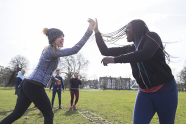 Enthusiastische Frauen, die sich im sonnigen Park die Hände reichen und Sport treiben - CAIF21157