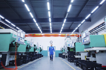 Worker walking through small parts manufacturing factory in China - CUF43446