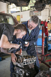 Mechanics working on car engine in garage - CUF43460