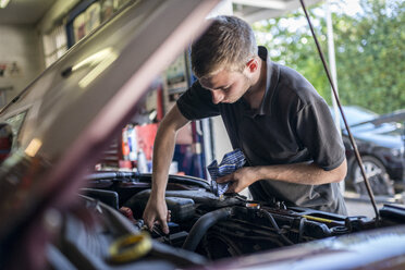 Mechaniker arbeitet an einem Auto mit geöffneter Motorhaube - CUF43461