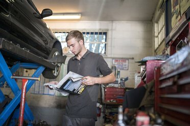 Mechaniker liest Handbuch in der Werkstatt - CUF43462