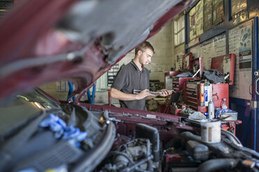Mechaniker hält Werkzeug in der Garage - CUF43463