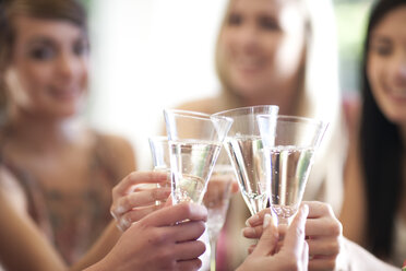 Gruppe von Freundinnen stößt mit einem Glas Champagner an - CUF43466