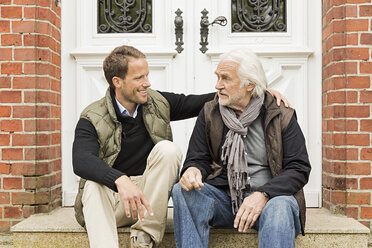 Father and son sitting on doorstep - CUF43470