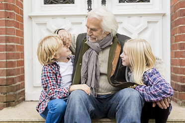 Grandfather sitting with grandchildren on front doorstep - CUF43499