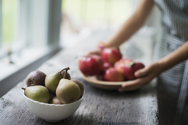 A person preparing organic fresh produce in a kitchen. Apples. Bowl of pears. - MINF00064