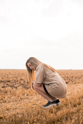 Junge Frau hockt auf einem Feld - ACPF00119