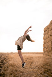 Happy young woman jumping in field - ACPF00120