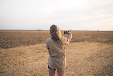 Junge Frau steht auf einem Feld und macht ein Smartphone-Selfie - ACPF00134