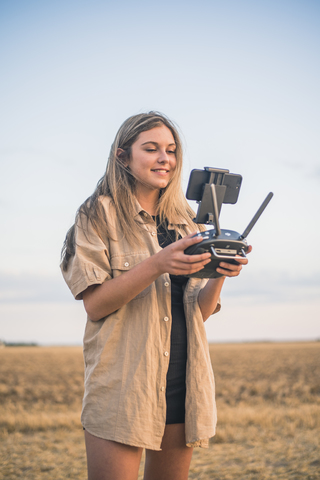 Junge Frau auf dem Lande mit Drohne, lizenzfreies Stockfoto
