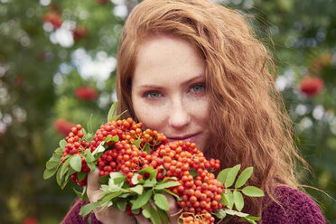 Portrait of freckled redheaded young woman with rowanberries - ABIF00712