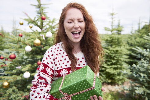 Portrait of redheaded woman with Christmas present crying of joy - ABIF00720