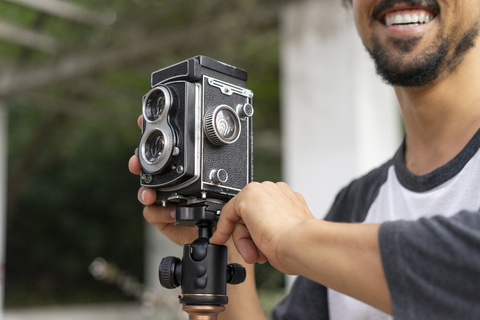 Close-up of happy young man using vintage camera stock photo