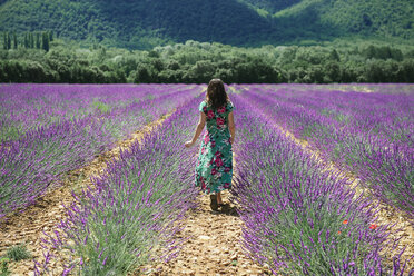 Frankreich, Provence, Hochebene von Valensole, Frau geht zwischen Lavendelfeldern im Sommer spazieren - GEMF02152