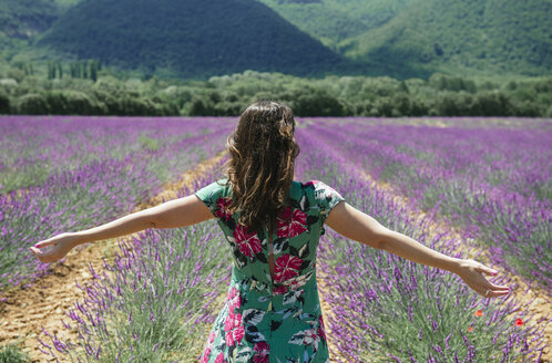 Frankreich, Provence, Valensole-Plateau, Frau steht mit ausgestreckten Armen in Lavendelfeldern im Sommer - GEMF02153