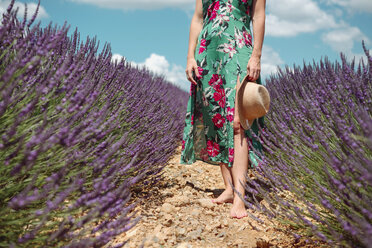 Frankreich, Provence, Hochebene von Valensole, Barfüßige Frau inmitten von Lavendelfeldern im Sommer - GEMF02158