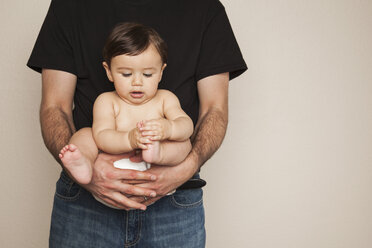 Ein kleiner Junge in Stoffwindeln wird von seinem Vater in den Arm genommen. - MINF00188