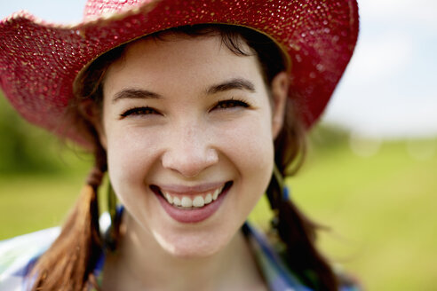 Eine junge Frau mit einem rosafarbenen Strohhut lächelt breit. - MINF00198