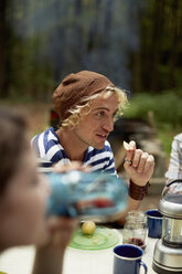 Ein junger Mann sitzt an einem Picknicktisch im Wald. - MINF00205
