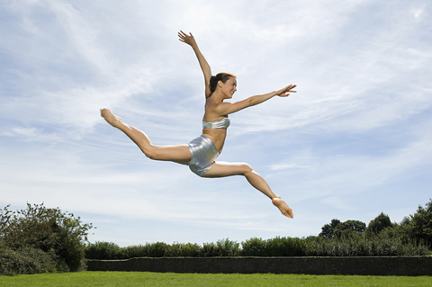 Eine junge Frau, die in die Luft springt, ein Akrobat., lizenzfreies Stockfoto