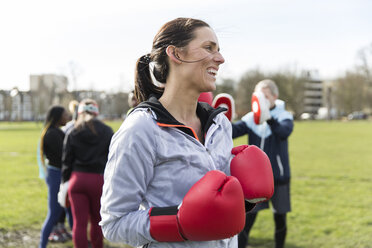 Lächelnde, selbstbewusste Frau beim Boxen im Park - CAIF21180