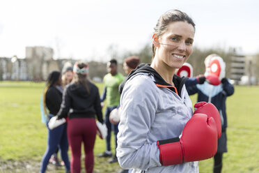 Portrait lächelnde, selbstbewusste Frau beim Boxen im Park - CAIF21194