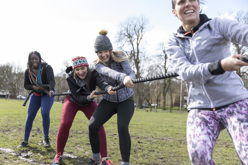 Entschlossene Frauen ziehen beim Tauziehen im sonnigen Park an einem Seil - CAIF21203