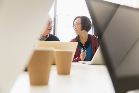 Geschäftsleute im Gespräch, die Laptops in einem Konferenzraum benutzen, lizenzfreies Stockfoto