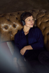 Woman with headphone lying on sofa, listening music - RBF06441