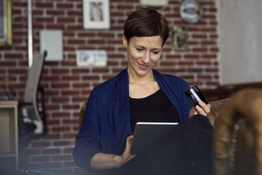 Woman sitting on sofa, using digital tablet, shopping online - RBF06444