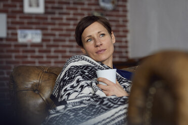 Woman on sofa relaxing at home, drinking tea - RBF06446