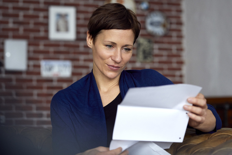 Woman reading letter at home stock photo