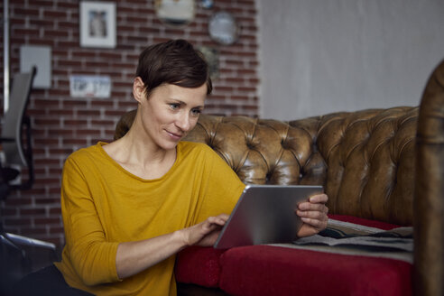 Woamn sitzt zu Hause und benutzt ein digitales Tablet - RBF06450