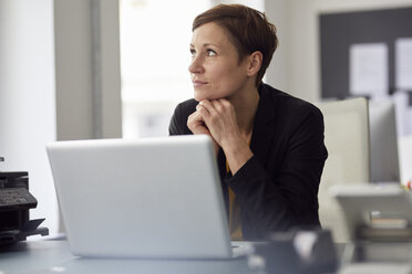 Businesswoman sitting in office, using laptop - RBF06457