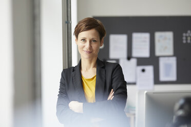 Attractive businesswoman standing in office with arms crossed - RBF06458