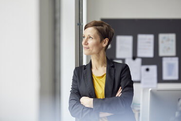 Attractive businesswoman standing in office with arms crossed - RBF06459