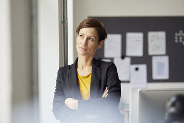 Attractive businesswoman standing in office with arms crossed - RBF06460