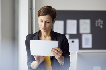 Attraktive Geschäftsfrau im Büro stehend, mit digitalem Tablet - RBF06464