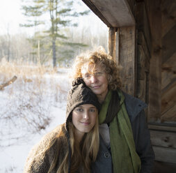 Zwei Menschen, eine Mutter und eine Tochter, nebeneinander in der Veranda einer Holzscheune auf einem Bauernhof. Ein Wintertag. - MINF00227