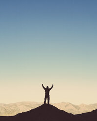 Silhouette eines männlichen Wanderers, der einen Rucksack trägt und auf einer Bergkuppe im Death Valley National Park steht. - MINF00236