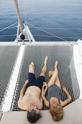 Älteres Paar auf einem Segeltörn auf einem Trampolin liegend, entspannend - EBSF02582