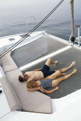 Mature couple on a sailing trip lying on trampoline, relaxing - EBSF02583