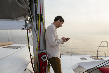 Marure man on catamaran, using smartphone - EBSF02607