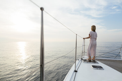 Mature woman standing on catamaran, watching sunset - EBSF02626