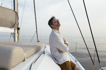 Marure man on catamaran with arms crossed, enjoying the breeze - EBSF02635